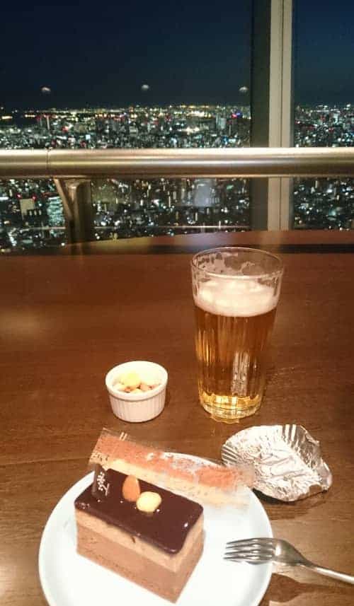 A photo of cake, beer and, nuts with a view of Tokyo in the background