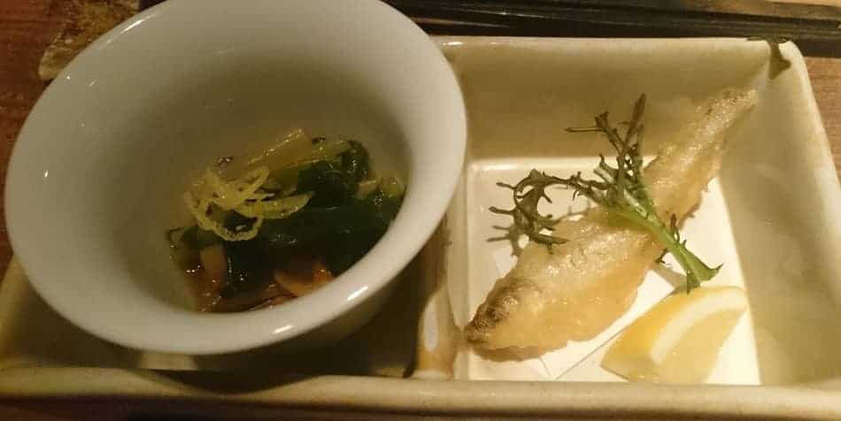 Otoshi. Closeup of salad and a small fried fish. This results in a table charge.