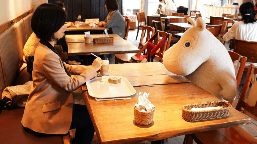 A woman having lunch with a moomin in Moomin House Café in Tokyo.